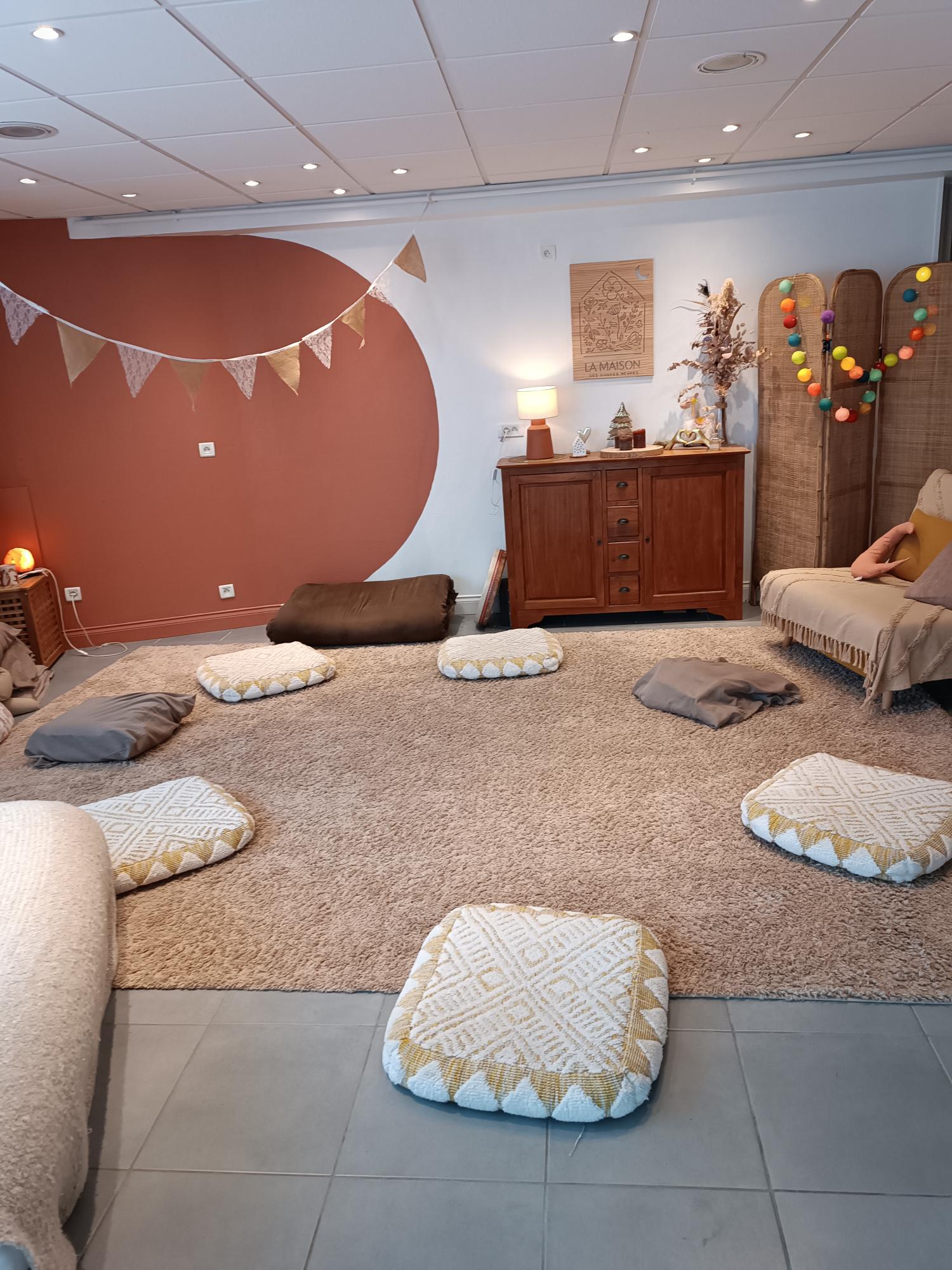 une salle avec un tapis sur lequel plusieurs coussins beiges sont posées